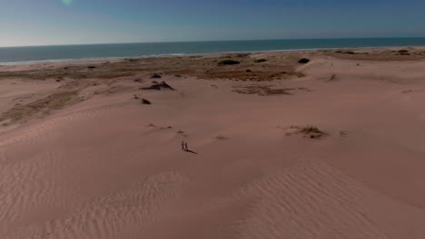 AERIAL---Two-people-on-beach,-Mar-Chiquita-salt-lake,-Cordoba,-Argentina,-truck-right