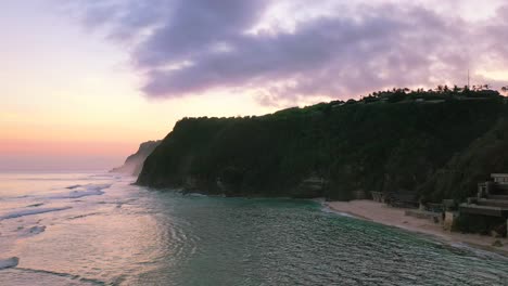 Luftstrandküste-Von-Uluwatu-Klippen-Mit-Purpurrotem-Und-Rosafarbenem-Sonnenuntergang-In-Bali