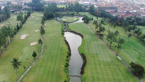 Luxury-golf-course-with-water-pond-in-Magelang,-Indonesia,-aerial-drone-view