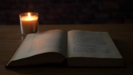 Lighting-a-candle-next-to-an-old-book-in-a-dark-room