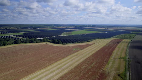 Aerial-View-Of-Large-Scale-Solar-Farm-Seen-In-Background-Next-To-Rural-Farmland