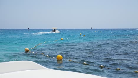View-from-a-boat,-watching-a-speedboat-race-across-the-beautiful-blue-sea