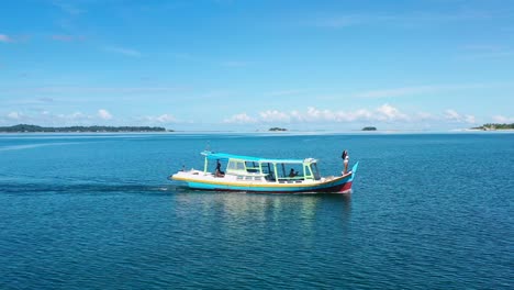 Luftaufnahme-Eines-Braunen-Mädchens,-Das-An-Einem-Sonnigen-Sommertag-In-Den-Tropischen-Gewässern-Von-Belitung-Indonesien-Auf-Dem-Bug-Des-Bootes-Steht