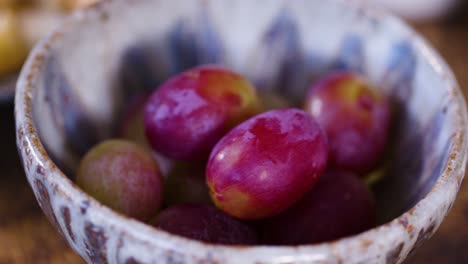 Small-bowl-with-red-grapes-being-placed-down,-close-up-shot
