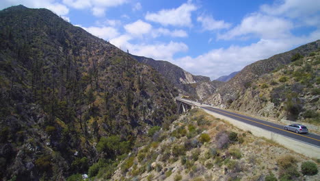 Drone-shot-of-cars-traveling-towards-Big-Tujunga-Narrows-Bridge-in-southern-California