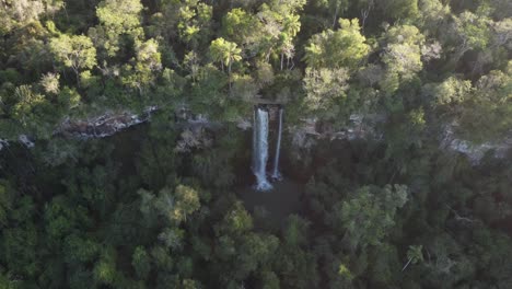 Cinematic-drone-backwards-shot-of-falling-water-of-Waterfall-in-middle-of-Amazon-Rainforest-jungle-during-sunset