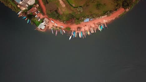 Top-View-Of-Wooden-Fishing-Boats-Docked-On-The-Shore-Of-Lake-Bunyonyi,-Uganda