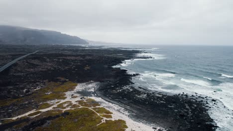 Aerial-shot-of-exotic-black-sand-beach,-rough-wavy-ocean-4k