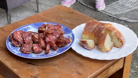 Homemade-sausage-and-home-baked-bread-on-the-plate,-in-the-rural-countryside,-Croatia