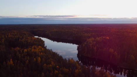 rotating-reveal-of-setting-sun-over-a-forest-and-mirror-like-surface-of-a-lake