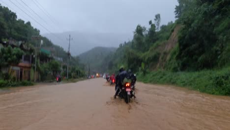 Motorcycles-driving-on-a-road-flooded-by-very-muddy-storm-waters-during-a-typhoon-in-Nepal
