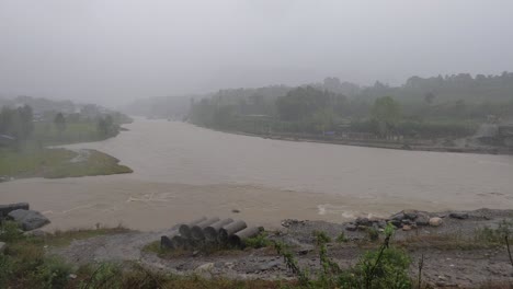 Ein-Hochwinkeliger-Schwenkblick-Auf-Die-Tobenden-Hochwasser-In-Einem-Fluss-Von-Einem-Taifun-In-Indien-Während-Des-Starken-Regens-In-Nepal