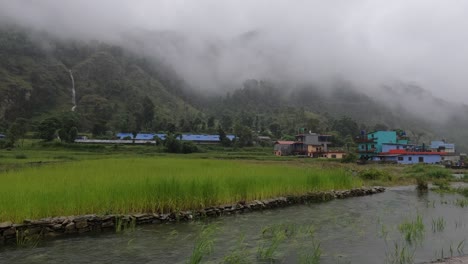 Ein-Blick-Auf-Die-Reisfelder-Mit-Hochwasser-Im-Vordergrund-Und-Nebelverhangenen-Bergen-Im-Hintergrund-Während-Eines-Heftigen-Regensturms-In-Nepal