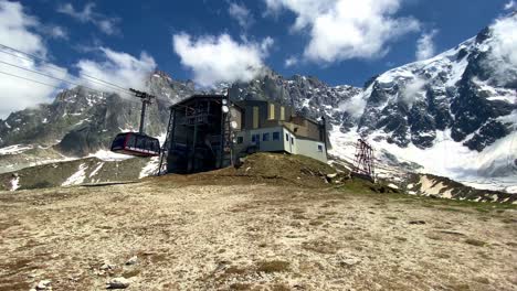 Cable-Car-Going-Up-To-Plan-de-l'Aiguille-Station-With-Rocky-Mountains-In-The-Background
