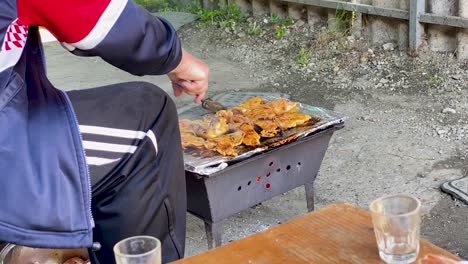 A-peasant-in-a-dirty-clothes-grills-chicken,-rural-Croatia