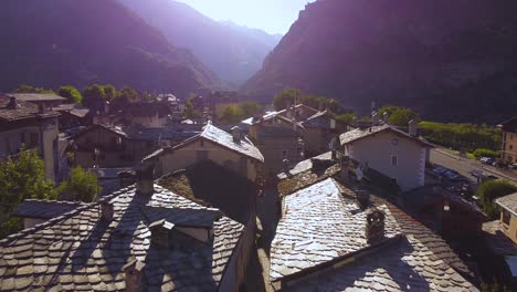 Italian-alps-village-next-to-mountains,-closing-aerial-drone-shot-with-backwards-motion