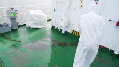 Slow-Motion-Video-4K-man-in-white-working-coat-washing-metal-floor-Water-that-washes-high-pressure-ship-deck-floors-from-a-pressure-washer