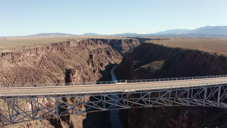Aerial-as-semi-truck-drives-over-deep-desert-canyon-on-large-bridge