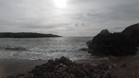 Relaxing-slow-motion-foaming-ocean-waves-crashing-against-rugged-Welsh-coastline-at-sunrise