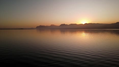 Peaceful-scene-of-water-ripples-on-a-lagoon-as-the-sun-sets-with-mountains-in-the-distance