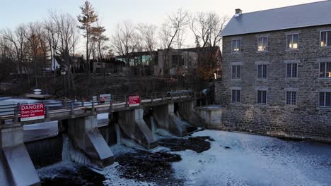Watson's-mill-dam-in-late-fall-early-winter-with-ice-forming-on-the-rideau-river-in-the-small-country-town-of-Manotick-near-Ottawa