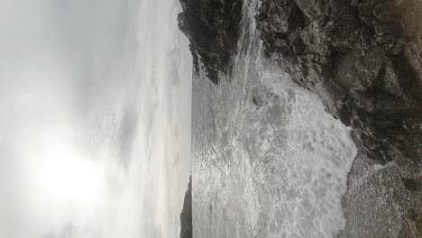 VERTICAL-slow-motion-ocean-waves-crashing-against-Anglesey-rock-coastline-at-sunrise