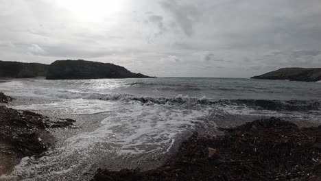 Slow-motion-foaming-ocean-waves-movement-breaking-against-rugged-Welsh-shoreline-at-sunrise
