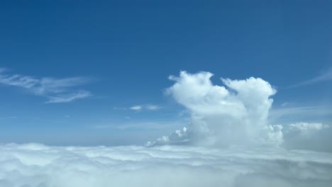 Aerial-view-toward-a-tiny-cumulus-top-taken-from-a-jet-cockpit-at-10000m-high-druise-level-with-a-deep-blue-sky