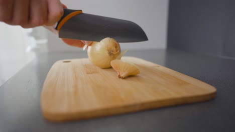 Man-slicing-a-brown-onion-with-a-kitchen-knife