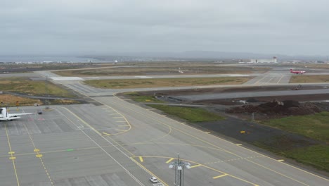 Distant-airplane-landing-on-airport-runway-in-Iceland-on-grey-cloudy-day,-aerial