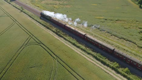 Aerial-view-of-a-steam-engine-locomotive-train-passing-on-tracks-in-the-countryside-in-England