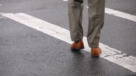 Low-angle-close-up-of-man-wearing-formal-dress-pants-and-shoes-while-crossing-the-street