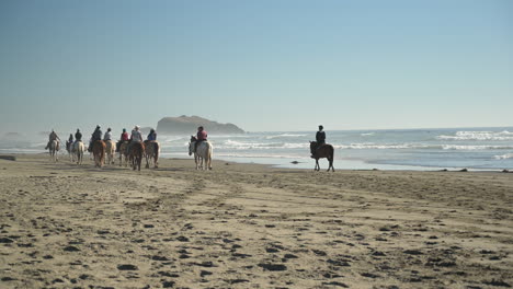 A-group-of-people-riding-horses-at-Bandon-Beach,-Oregon-Coast