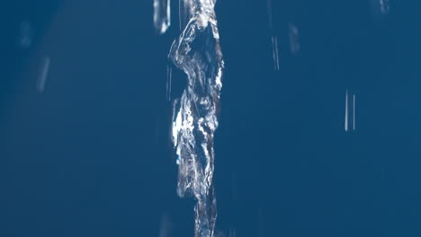 Real-pure-water-flowing-down-with-splashing-on-blue-background-shooting-in-slow-motion