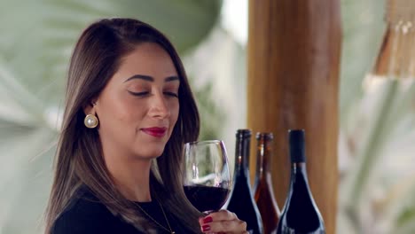 lady-with-a-glass-of-red-wine-with-three-bottles-in-the-background-on-a-wine-tasting---close-up-slow-motion