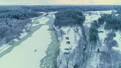 Nordic-winter-landscape,-countryside-forested-area-near-forzen-river,-Aerial-Orbiting
