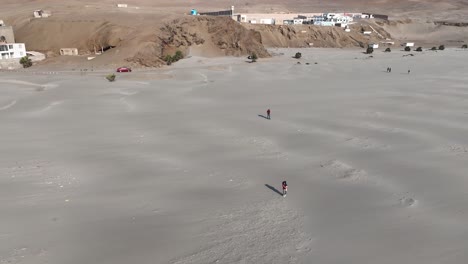 Aerial-spinning-shot-from-the-beautiful-beach-caleta-vidal-in-peru-with-people-running-in-the-sand-and-view-of-the-city-and-the-sea-with-calm-waves-on-a-cloudless-summer-day