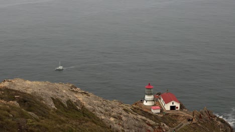 Medium-shot-of-the-Point-Reyes-lighthouse-with-lone-boat-on-the-ocean-behind