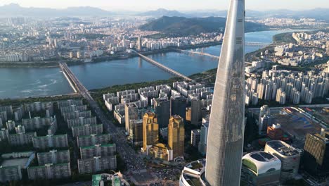 Timelapse-drone-shot-of-Lotte-World-Tower-at-sunset-with-Songpa-district-and-Han-River,-Seoul,-South-Korea