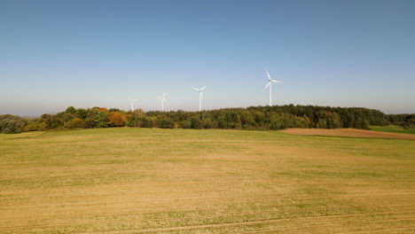 Evening-view-of-autumn-forest-and-wind-turbines-or-windmills-farm-field-in-the-background