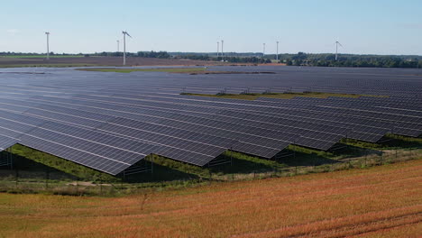 Photovoltaikpark-Mit-Einer-Großen-Anzahl-Von-Sonnenkollektoren---Windkraftanlagen-Im-Hintergrund