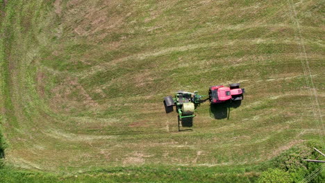 Traktor-Sammelt-Heuballen-Auf-Dem-Feld---Antenne-Von-Oben-Nach-Unten