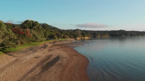 Aerial-drone-view-of-Cornwallis-Beach-in-Auckland,-New-Zealand,-slow-low-straight-flight