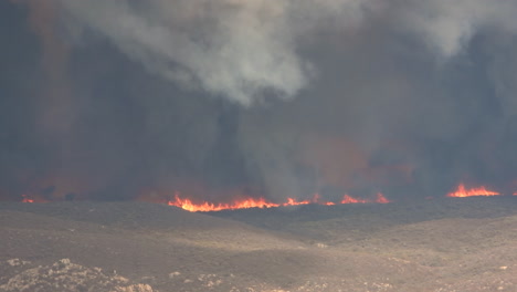 Masses-of-dense-black-smoke-filling-the-air-with-a-wildfire-burning-below