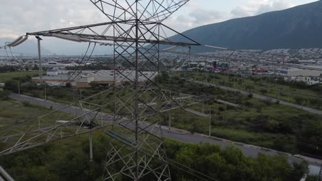 electric-tower-with-a-huge-cords-runnnin-from-one-end-to-the-other-electricity-high-voltage-running-throw-it-in-the-middle-of-a-city-and-a-mountain-in-the-background