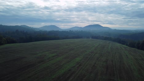 Drone-view-of-morning-field-with-mist-and-haze-in-background,-Kokorinsko,-Czech-Republic-nature