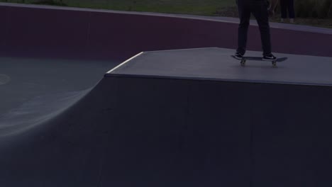 Slow-motion-shot-of-boy-doing-on-ollie-on-rail-at-a-skate-park-skateboarding-during-sunset
