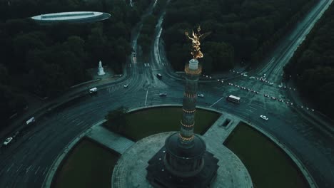 Drone-aerial-of-Berlin-Victory-Column-before-sunrise-with-trees-all-around-and-cars-on-round-about