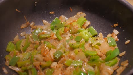 Close-up-of-huge-wok-while-frying-onions-and-green-bell-peppers-in-oil-and-deep-pan