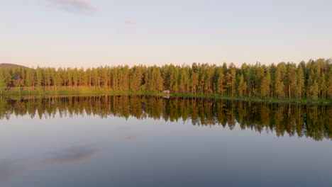 Bosque-De-Abetos-Con-Reflejo-De-Espejo-En-Un-Lago-Transparente-En-Laponia,-En-El-Norte-De-Suecia
